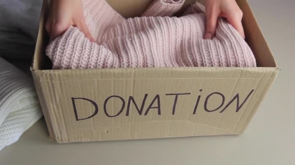 Vrouw vouwt warme kleren in donatie doos — Stockvideo