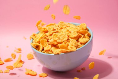 Lezzetli mısır gevrekleri renkli bir arka planda bir tabağa düşüyor..