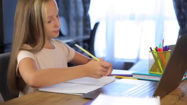 Школьница учится онлайн с помощью современного ноутбука. Домашняя работа — стоковое видео