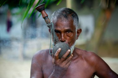Bangladeş, Narsingdi Bölgesi 'nde hindistan cevizi kabuğundan yapılma ahşap pipo ve balçıktan yapılmış kırsal bir sigara aleti kullanan yaşlı bir köylü..