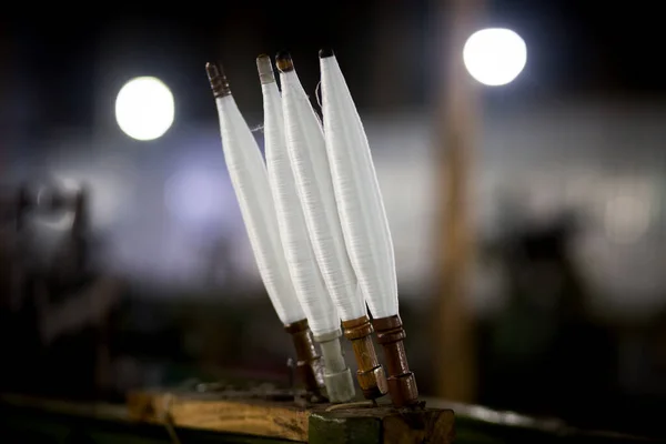 Bir iplik fabrikasında beyaz iplik makaraları. Koyu arkaplanda beyaz iplik makaraları.