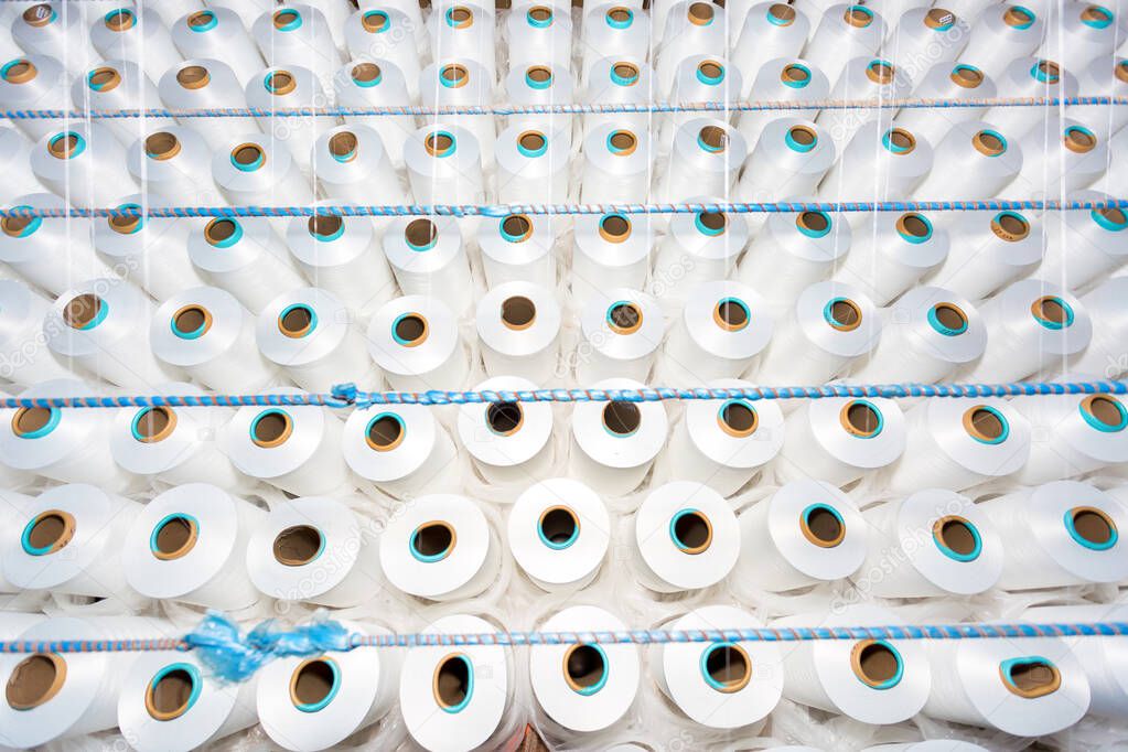 Top view of A lot of white yarn spools in a textile factory. White yarn spools in a clothing factory.