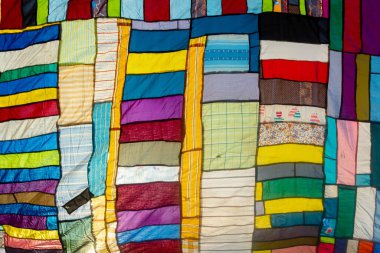 Bir terzi tarafından kullanılmamış ve toplanmış rengarenk giysilerin kombinasyonundan yapılmış büyük renkli sanatsal bir kumaş..