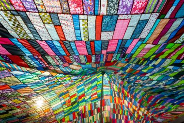 Bir terzi tarafından kullanılmamış ve toplanmış rengarenk giysilerin kombinasyonundan yapılmış büyük renkli sanatsal bir kumaş..