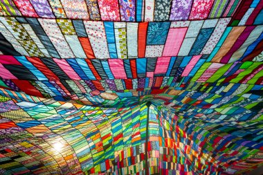 Bir terzi tarafından kullanılmamış ve toplanmış rengarenk giysilerin kombinasyonundan yapılmış büyük renkli sanatsal bir kumaş..