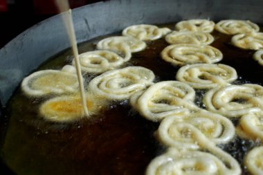 Jilapi hamuru jalebi yapmak için kızgın yağın içine karıştırılıyor..