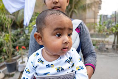 Bir anne, sevimli bebeğiyle taşınabilir bir çantanın içinde eğleniyor. Sevgi dolu sevgi dolu duygular. Aile ilişkisi ve anne-bebek bakımı kavramı.
