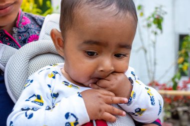 Tatlı, tombul bir oğlan çocuğu ağzıyla parmağını emiyor. Kafasına yakın çekim..
