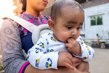 Tatlı, tombul bir oğlan çocuğu ağzıyla parmağını emiyor. Kafasına yakın çekim..