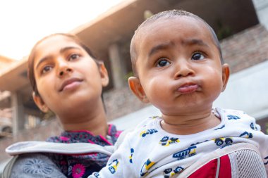 Bir anne, sevimli bebeğiyle taşınabilir bir çantanın içinde eğleniyor. Sevgi dolu sevgi dolu duygular. Aile ilişkisi ve anne-bebek bakımı kavramı.