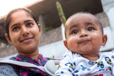 Bir anne, sevimli bebeğiyle taşınabilir bir çantanın içinde eğleniyor. Sevgi dolu sevgi dolu duygular. Aile ilişkisi ve anne-bebek bakımı kavramı.