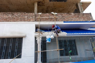 Joypara, Dohar, Dhaka, Bangladeş 'teki bir binanın beton duvarını tehlikeli ve riskli yollarla boyayan iki işçi. 18 Şubat 2021.