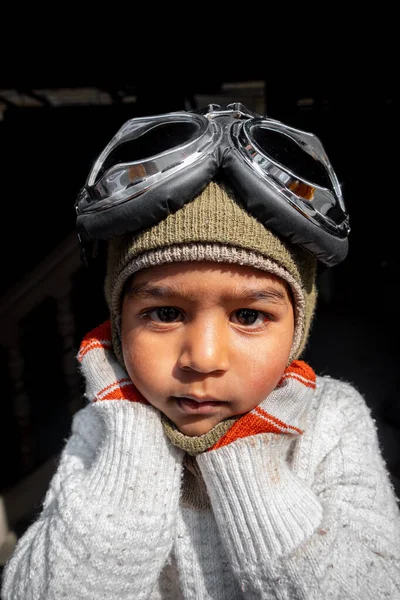 A boy pilot covers his ears with both hands as a crash and a bombing-style pose. Asian boy pilot in vintage aviator helmet & goggles.