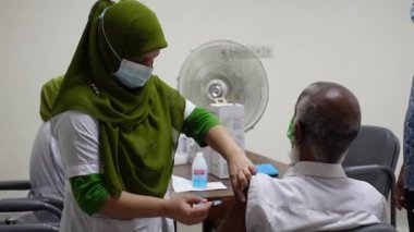 Sağlık çalışanı Bangladeş 'in Dhaka kentindeki Matuail Çocuk ve Anne Sağlığı Enstitüsü' nde (ICMH) bir kişinin vücuduna hükümet tarafından sağlanan Covid-19 aşısını enjekte ediyor. 16 Ağustos 2021.