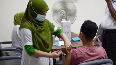 Sağlık çalışanı Bangladeş 'in Dhaka kentindeki Matuail Çocuk ve Anne Sağlığı Enstitüsü' nde (ICMH) bir kişinin vücuduna hükümet tarafından sağlanan Covid-19 aşısını enjekte ediyor. 16 Ağustos 2021.