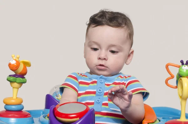 Очаровательный шестимесячный ребенок смотрит на свои игрушки . — стоковое фото