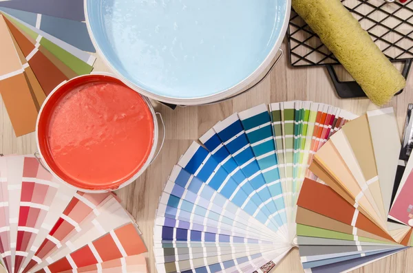 Latas y muestras de pintura azul y roja con diferentes tonos de color con rodillo de pintura y accesorios . — Foto de Stock