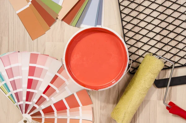 Coral red paint can. Samples with different shades of red and can of red paint with paint roller and accessories. — Stock Photo, Image