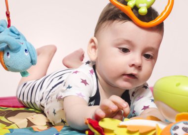 Bir playmat üzerinde oturan ve oyuncaklar ile oynama şirin bebek çocuk. 