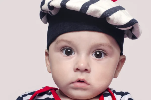 Adorável criança de seis meses usando um chapéu listrado marinho . — Fotografia de Stock