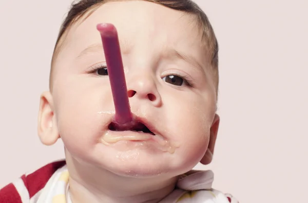 Enfant drôle essayant de se nourrir de nourriture pour bébé tenant la cuillère dans la bouche . — Photo