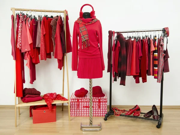 Wardrobe with red clothes arranged on hangers and an outfit on a mannequin. — Stock Photo, Image