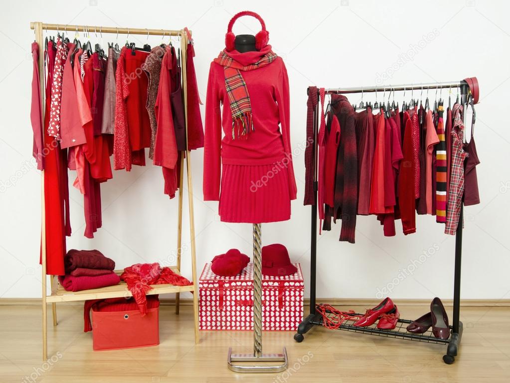 Wardrobe with red clothes arranged on hangers and an outfit on a mannequin.