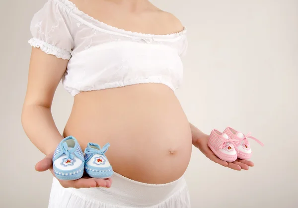 Zblízka na břichu s růžové a modré novorozence boty.. — Stock fotografie