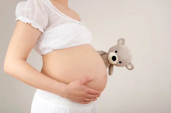 Close up on pregnant belly with toy. — Stock Photo, Image