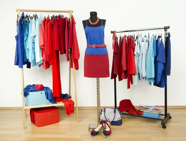 Wardrobe with red and blue clothes arranged on hangers. — Stock Photo, Image