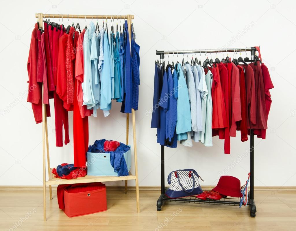 Wardrobe with red and blue clothes hanging on a rack nicely arranged.