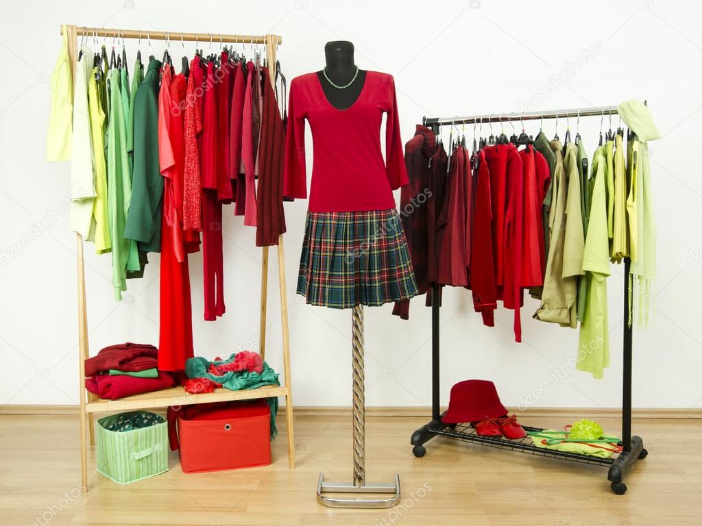 Dressing closet with complementary colors red and green clothes arranged on hangers and a plaid outfit on a mannequin.