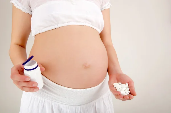 Närbild på gravid mage med medicin... Ta droger eller vitaminer under graviditet koncept. — Stockfoto