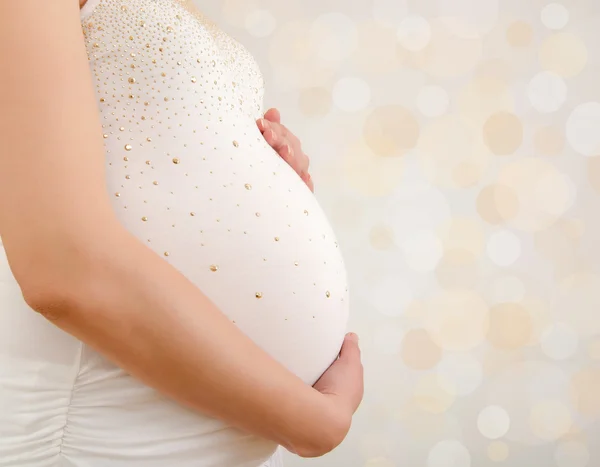 Nahaufnahme einer Frau, die ihren schwangeren Bauch festhält. — Stockfoto