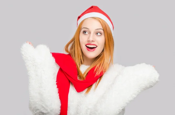 Schöne junge Frau mit Weihnachtsmütze lächelnd zur Seite schauend überrascht. — Stockfoto