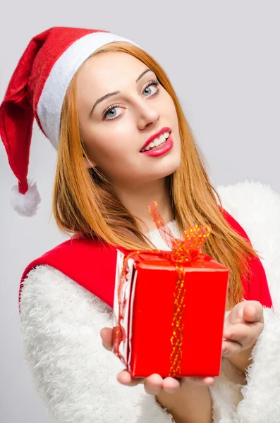 Mooie jonge vrouw met op de voorgrond een kerstcadeau. — Stockfoto