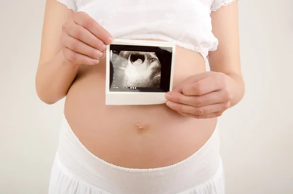 Close up on pregnant belly with baby's ultrasound. — Stock Photo, Image