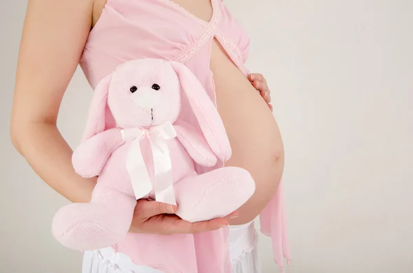 Close up on pregnant belly with toy. — Stock Photo, Image