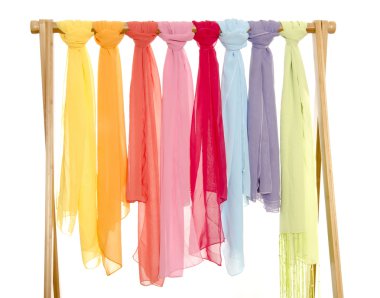 Color coordinated scarves arranged on a rack. clipart
