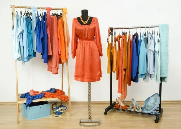 Wardrobe with complementary colors orange and blue clothes arranged on hangers. — Stock Photo, Image