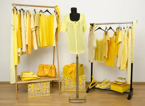 Vestiaire avec des vêtements jaunes disposés sur des cintres et une tenue sur un mannequin . — Photo