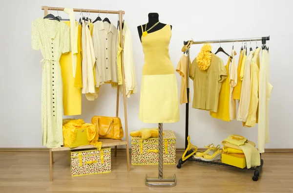 Klä garderob med gula kläder på galgar och en outfit på en skyltdocka. — Stockfoto