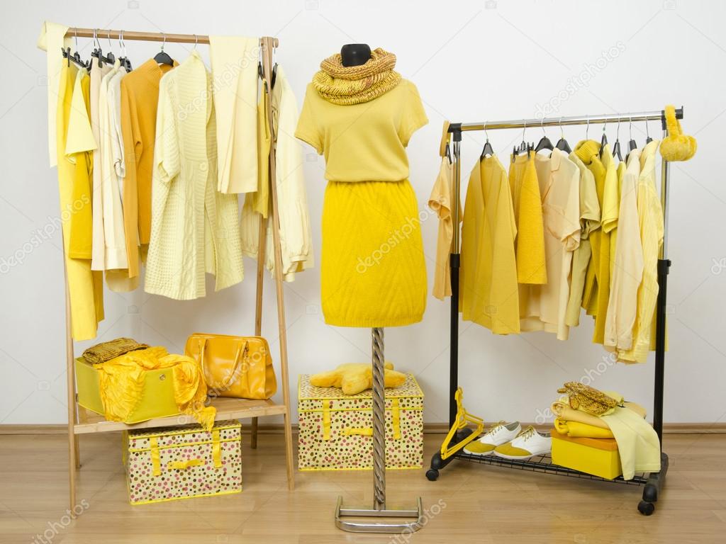 Dressing closet with yellow clothes arranged on hangers and a winter outfit on a mannequin.