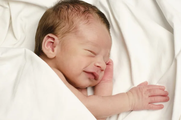 Nya född pojke ler i sömnen. — Stockfoto