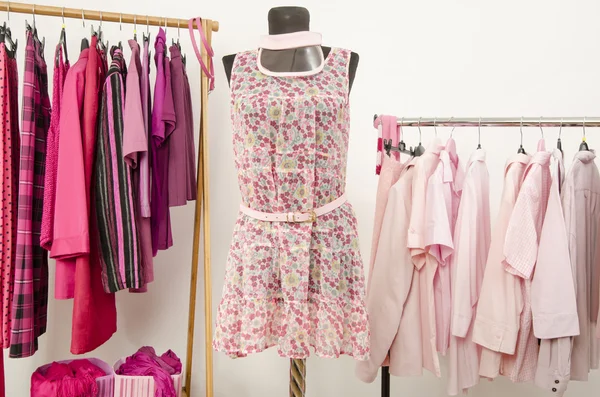 Kleiderschrank mit pinkfarbener Kleidung auf Kleiderbügeln und einem Sommeroutfit auf einer Schaufensterpuppe. — Stockfoto