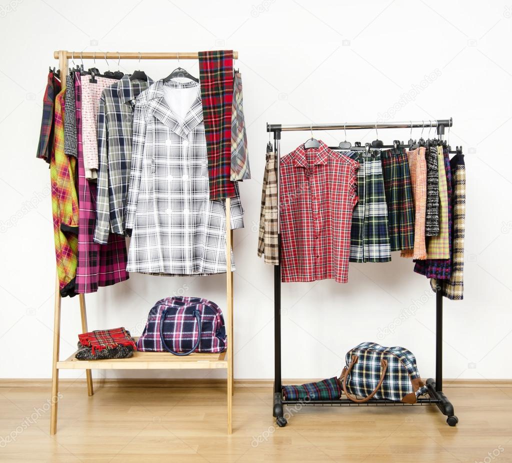 Dressing closet with plaid clothes arranged on hangers on racks.