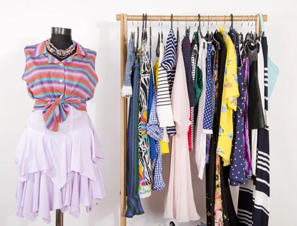 Dressing closet with colorful clothes arranged on hangers and a — Stock Photo, Image