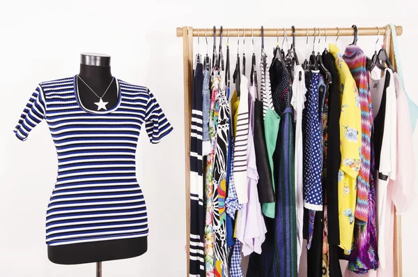 Dressing closet with colorful clothes arranged on hangers and an — Stock Photo, Image