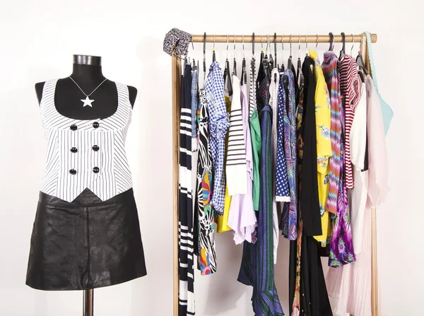 Dressing closet with colorful clothes arranged on hangers and an — Stock Photo, Image