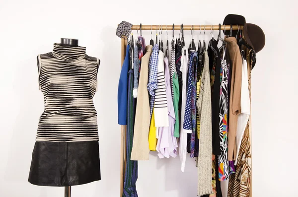 Kleiderschrank mit bunten Kleidern auf Kleiderbügeln und einem Outfit auf einer Schaufensterpuppe. — Stockfoto